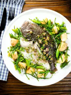 Overhead whole roast turbot with capers, new potatoes, samphire, asparagus, sugar snap peas and garden peas.