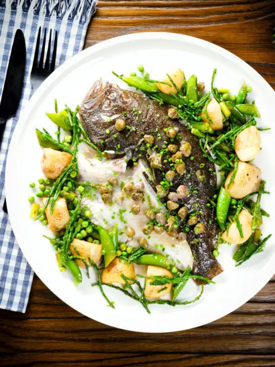Overhead whole roast turbot with capers, new potatoes, samphire, asparagus, sugar snap peas and garden peas.