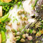 Overhead close-up whole roast turbot with capers, new potatoes and summer greens.