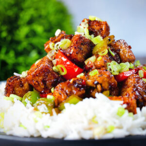 Spicy vegan (and vegetarian) Szechuan tofu with peppers and red onion served with white rice.