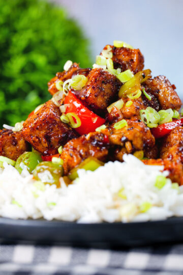 Close-up vegan/vegetarian Szechuan tofu with peppers and red onion served with white rice.