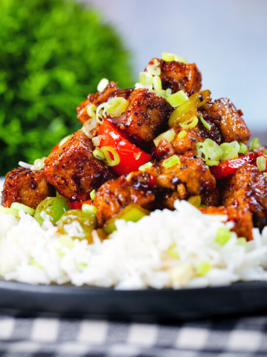 Close-up vegan/vegetarian Szechuan tofu with peppers and red onion served with white rice.