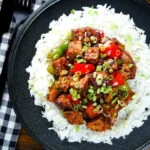 Overhead vegan/vegetarian Szechuan tofu with peppers and red onion served with white rice.