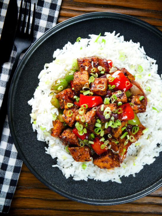 Overhead vegan/vegetarian Szechuan tofu with peppers and red onion served with white rice.