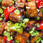 Close-up overhead vegan/vegetarian Szechuan tofu with peppers and red onion served with white rice.