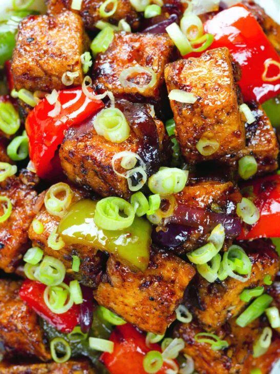 Close-up overhead vegan/vegetarian Szechuan tofu with peppers and red onion served with white rice.