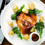 Overhead baked apple and bacon stuffed pork chops, with cider gravy, potatoes and broccoli.