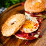 Bacon, egg, tomato and cheese breakfast bagels with sweet chilli sauce.