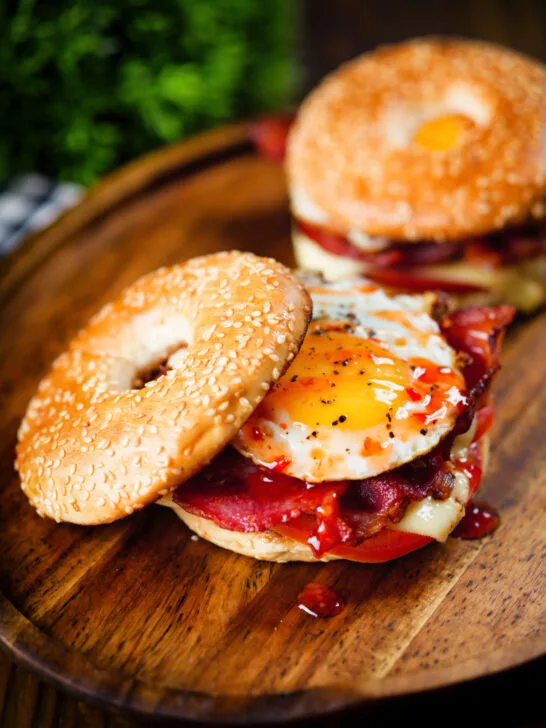 Bacon, egg, tomato and cheese breakfast bagels with sweet chilli sauce.