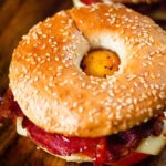 Close-up bacon, egg, tomato and cheese breakfast bagels with sweet chilli sauce.
