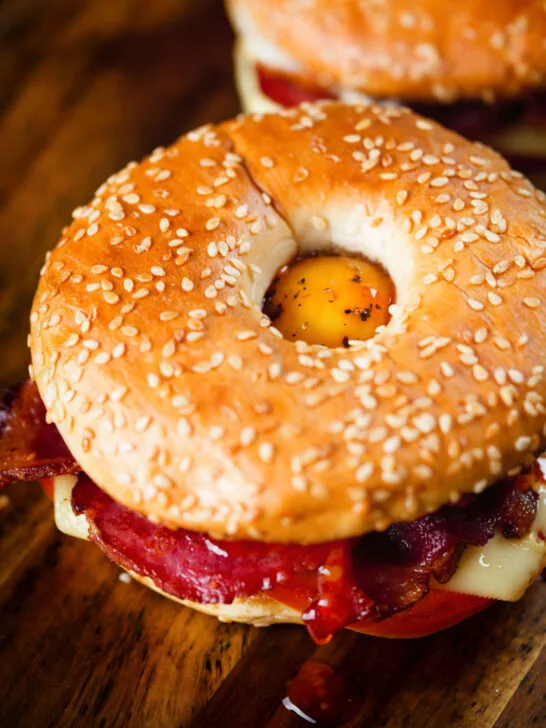 Close-up bacon, egg, tomato and cheese breakfast bagels with sweet chilli sauce.