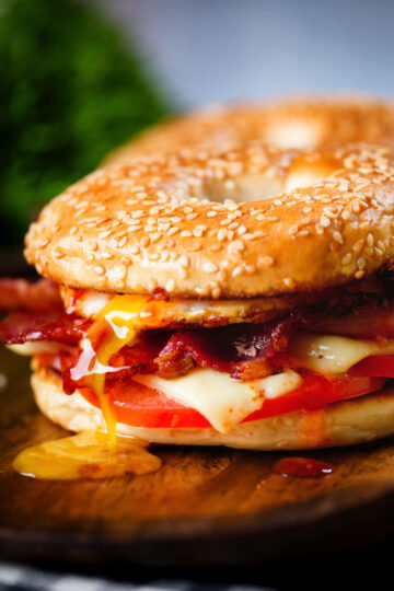 Bacon, egg, tomato and cheese breakfast bagels with a runny yolk and sweet chilli sauce.