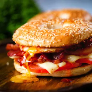 Bacon, egg, tomato and cheese breakfast bagels topped with sweet chilli sauce.