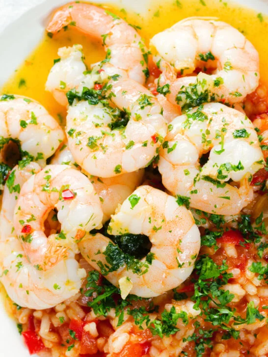 Close-up overhead Camarao à guilho (Portuguese garlic prawns) served with arroz con tomate.