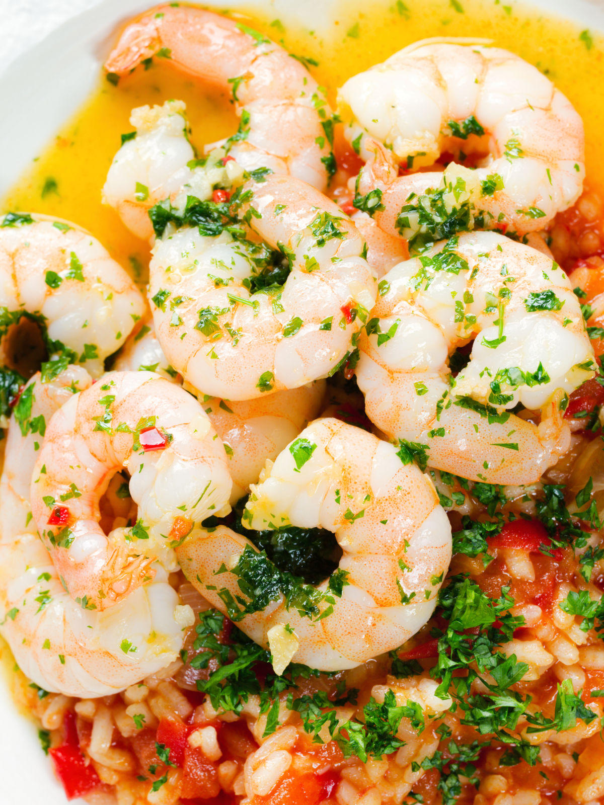 Close-up overhead Camarao à guilho (Portuguese garlic prawns) served with arroz con tomate.