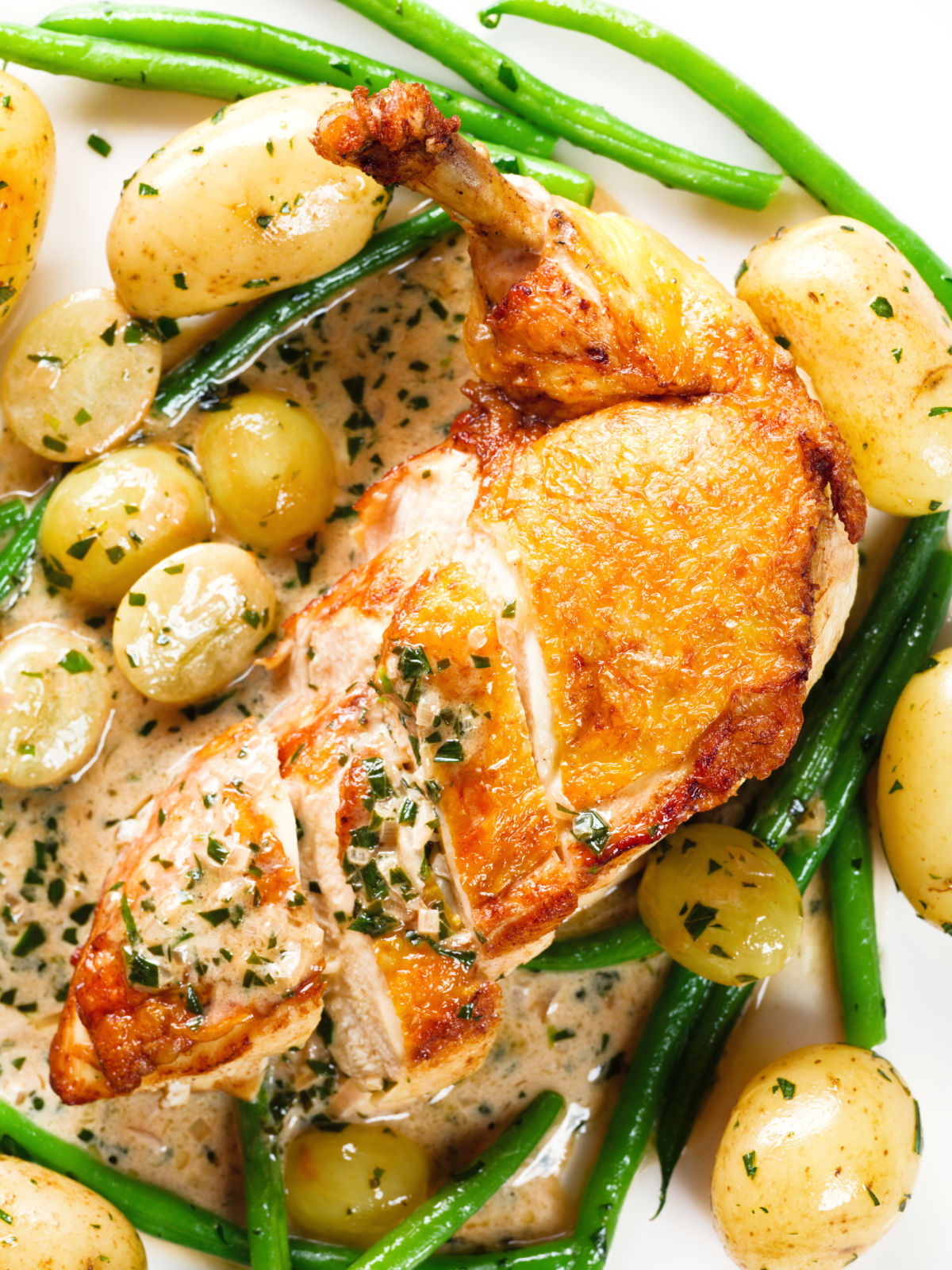 Close-up overhead chicken with Veronique sauce (grapes, vermouth and tarragon), new potatoes and fine beans.