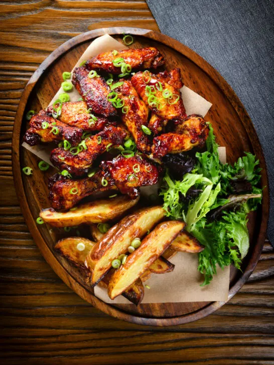 Overhead Chinese chicken wings with spare rib inspired glaze served with potato wedges.