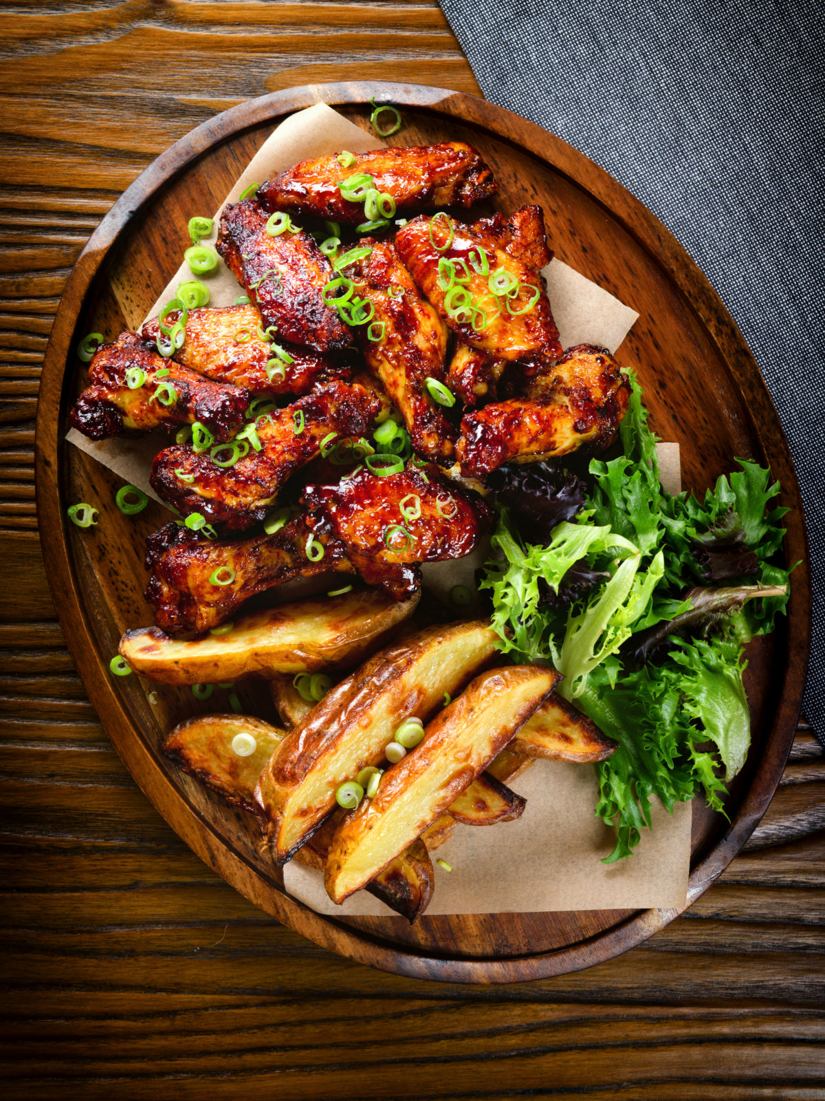 Overhead Chinese chicken wings with spare rib inspired glaze served with potato wedges.