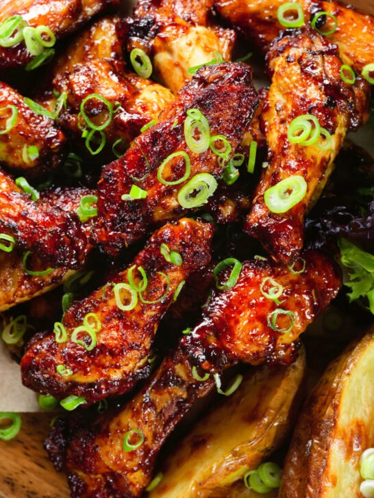 Overhead close-up Chinese chicken wings with spare rib inspired glaze served with potato wedges.
