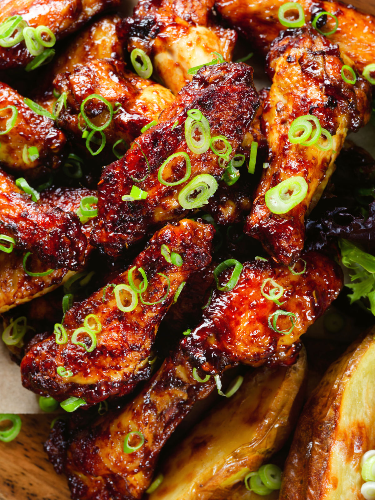 Overhead close-up Chinese chicken wings with spare rib inspired glaze served with potato wedges.
