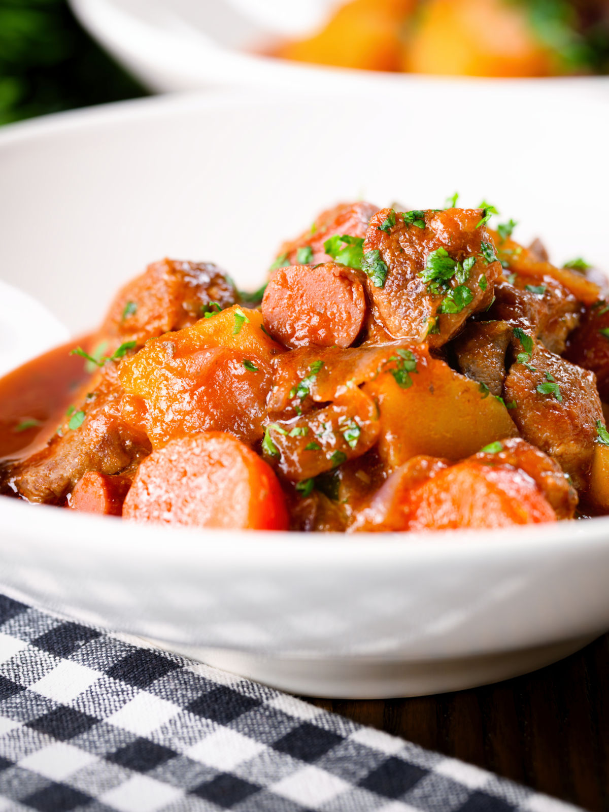 Close-up Filipino pork menudo with liver, hotdog sausages, potatoes and carrots.