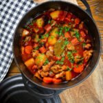 Overhead Filipino pork menudo with liver, hotdog sausages, potatoes and carrots in its cooking pot.