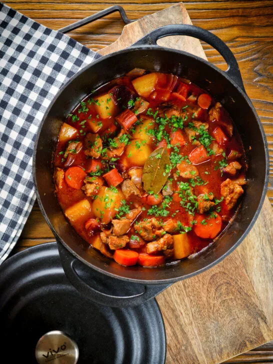 Overhead Filipino pork menudo with liver, hotdog sausages, potatoes and carrots in its cooking pot.