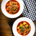 Overhead Filipino pork menudo with liver, hotdog sausages, potatoes and carrots.