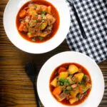 Overhead Filipino pork menudo with liver, hotdog sausages, potatoes and carrots.
