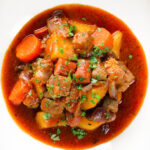 Close-up overhead Filipino pork menudo with liver, hotdog sausages, potatoes and carrots.