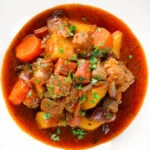 Close-up overhead Filipino pork menudo with liver, hotdog sausages, potatoes and carrots.