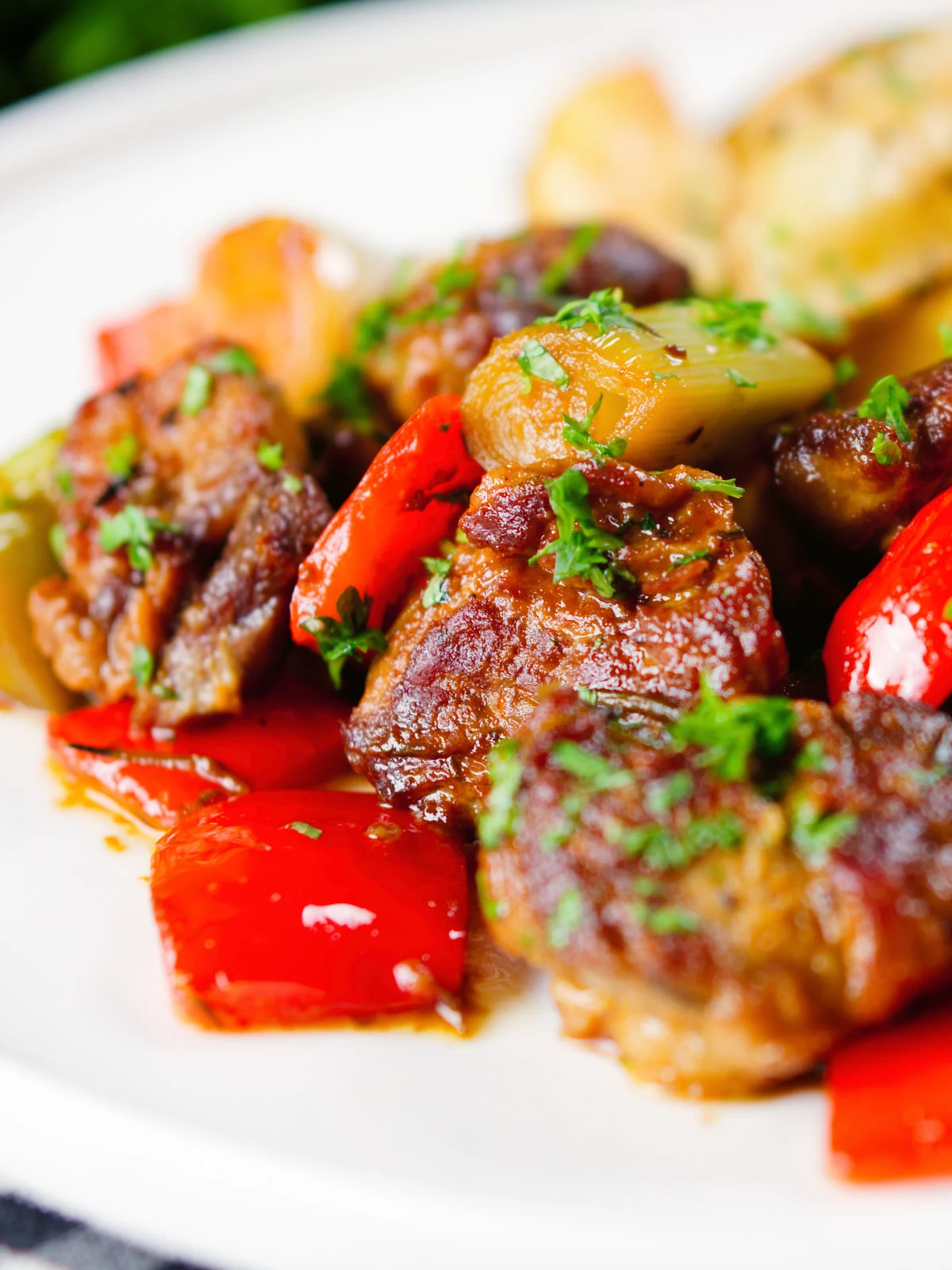 Close-up Greek pork tigania with peppers and leeks, served with watercress and potato wedges.