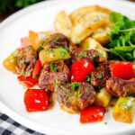 Greek pork tigania with peppers and leeks, served with watercress and potato wedges.