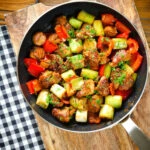 Overhead Greek pork tigania with peppers and leeks, served in a pan.
