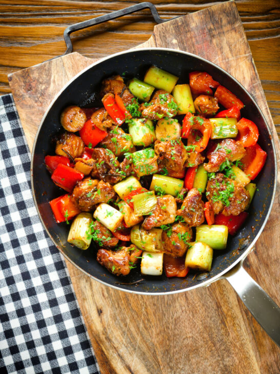 Overhead Greek pork tigania with peppers and leeks, served in a pan.
