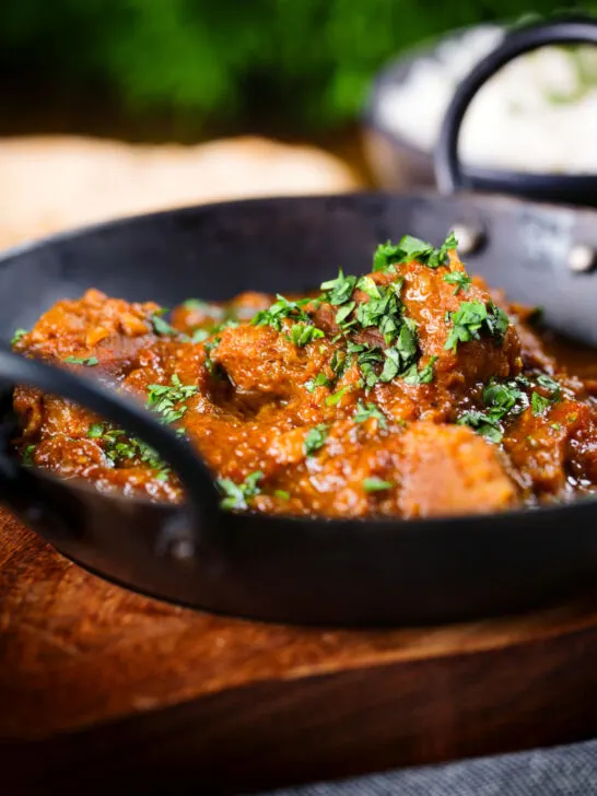 Close-up Indian (Goan) inspired pork vindaloo curry served with rice and naan bread.