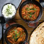 Overhead Indian (Goan) inspired pork vindaloo curry served with rice and naan bread.