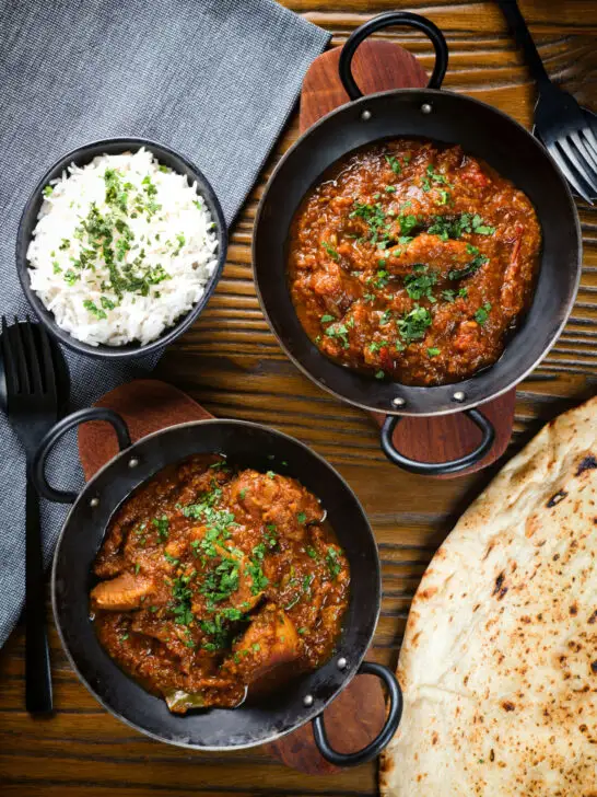 Overhead Indian (Goan) inspired pork vindaloo curry served with rice and naan bread.