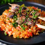 Portuguese beef espetada skewers served with tomato rice and parsley.