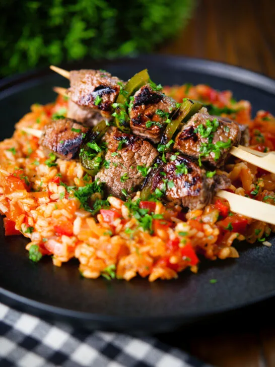 Portuguese beef espetada skewers served with tomato rice and parsley.