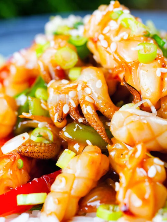 Close-up spicy squid stir fry in oyster sauce and crispy chilli oil served with white rice.