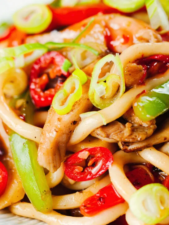 Close-up spicy stir fried sweet chilli chicken udon noodles with peppers.