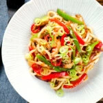 Overhead spicy stir fried sweet chilli chicken udon noodles with peppers.