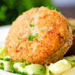 Close-up tinned salmon and sardine fish cake served with creamed leeks.