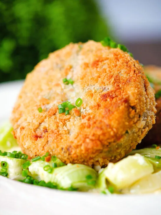 Close-up tinned salmon and sardine fish cake served with creamed leeks.