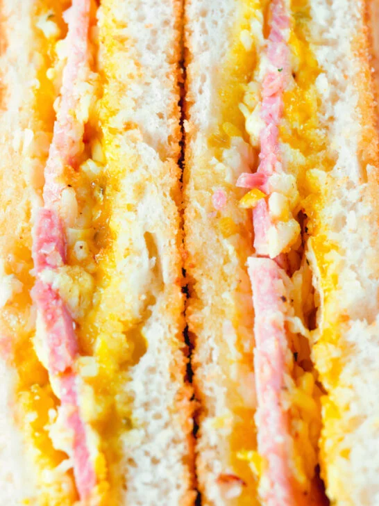 Close-up crispy air fryer cooked ham and cheese toastie with piccalilli.