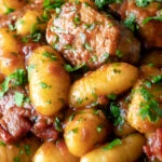 Close-up sausage gnocchi in a rich tomato sauce served with fresh parsley.