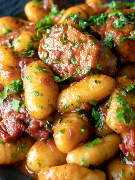 Close-up sausage gnocchi in a rich tomato sauce served with fresh parsley.