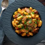 Overhead sausage gnocchi in a rich tomato sauce served.