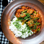 Overhead Indian beef & pork sausage curry with green beans served with plain rice.